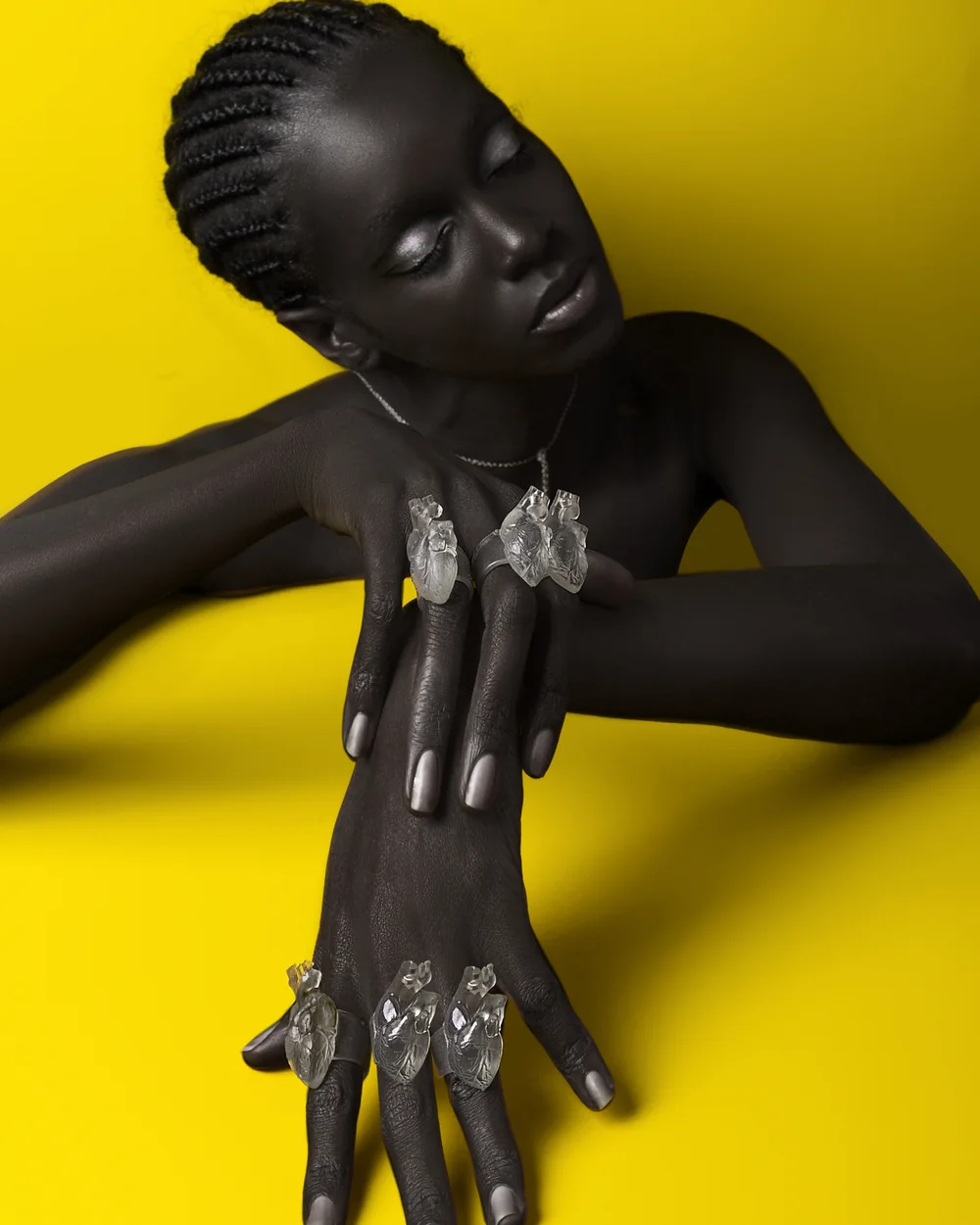 Daha Garcés con anillos de cristal en forma de corazón, sobre fondo amarillo